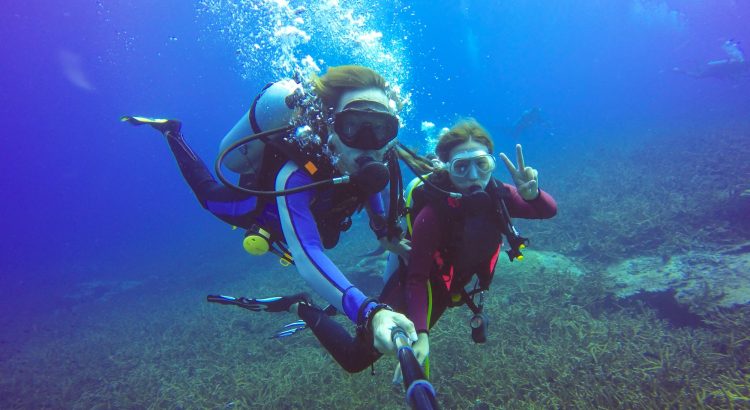 Underwater scuba diving selfie shot with selfie stick. Deep blue sea. Wide angle shot.